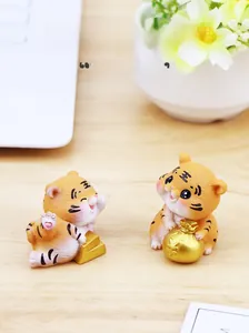 Nahaufnahme süßer Harz-Tigerfiguren mit Goldgeldsäcken auf einem Holzschreibtisch