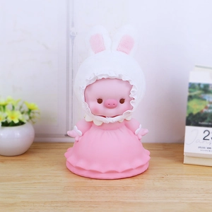 Cute pink pig money box with bunny ears hood and pink lace dress on wooden table