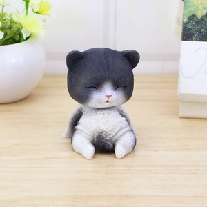 Figura de gato sonriente blanco y negro de resina sobre escritorio de madera con flores