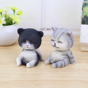 Detalle de dos lindas figuras de gatos sentados y sonrientes en un escritorio de madera