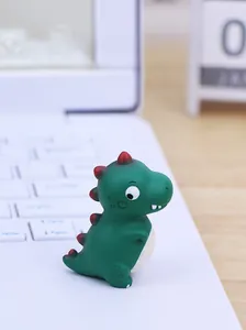 Nahaufnahme einer süßen dunkelgrünen Dinosaurier-Figur auf Laptop und Holzschreibtisch