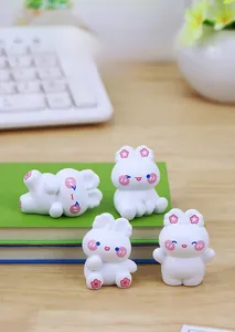 Set of four cute mini white resin bunny figurines on a desk with floral accents