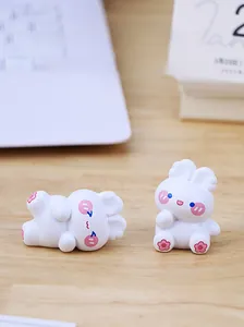 Close-up of two cute white resin bunny figurines in sitting and lying poses on a desk