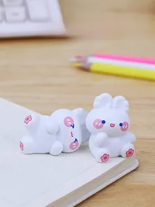 Close-up of cute white rabbit figurines on a desk with floral patterns and pink cheeks