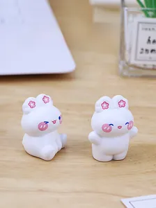 Close-up of two cute white resin bunny figurines with pink flower details on wood