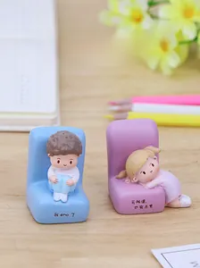Close-up of cute resin desk ornaments featuring boy and girl figurines in warm setting