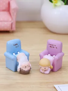 Close-up of cute resin miniature figures relaxing on blue and purple tiny sofas
