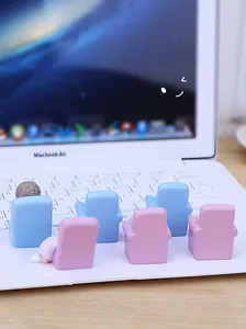 Miniature couple figures on blue and pink chairs placed on a laptop keyboard
