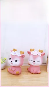 Detailed view of cute pink deer piggy banks with floral accents on a wooden surface