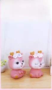 Detail view of two cute pink deer money boxes with flower decor on wooden surface
