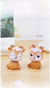Close-up of two cute resin deer figurines with flower crowns on a wooden desk