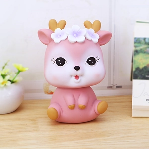 Pink cartoon deer money box in sitting pose with floral crown on wooden table