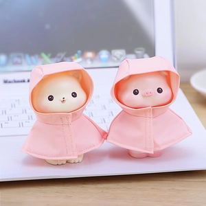 Figuras de resina de cerdo y gato con impermeables rosas sobre un teclado