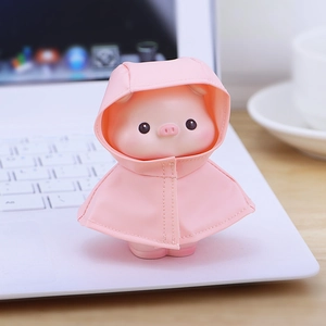 Figura de cerdito con impermeable rosa sobre el teclado de una laptop blanca
