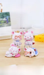 Lot de quatre figurines de souris roses en résine sur un bureau en bois chaleureux