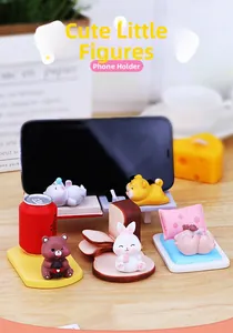 Cute resin cartoon animal phone stand on a wooden desk with cozy warm lighting