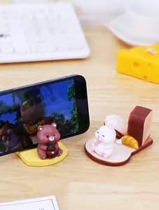 Detail of cute bear and rabbit resin phone stands on a cozy desktop with creative ornaments