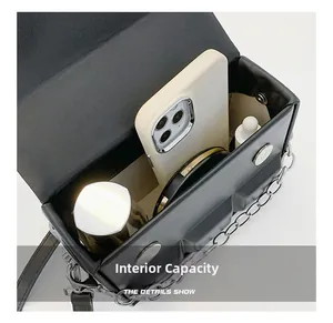 Detail showing internal capacity of the black leather box bag with makeup and phone