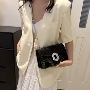 Fashionable black patent leather chain bag with sparkling rhinestone buckle on model