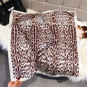 Detail of leopard print silk scarf with cream borders on soft plush background