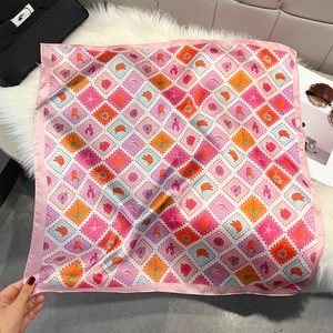 Detailed close-up of a satin square scarf featuring vibrant summer stamp patterns
