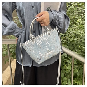 Close-up of silver sequins on trapezoid bucket bag with metallic handles