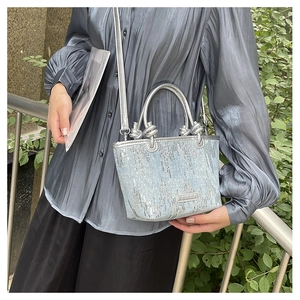 Close-up of silver sequin bucket bag with knotted handles and adjustable shoulder strap