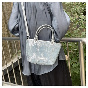 Detail of light blue sequin tote bag showing silver handles and shiny metallic finish