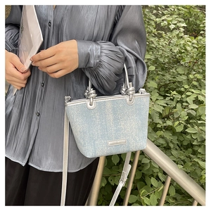 Detail of light blue sequined tote bag with silver knot handles and thin shoulder strap