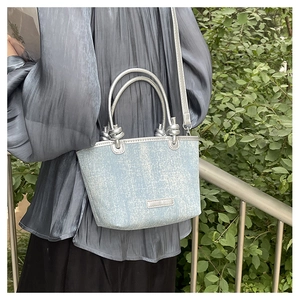 Detail of light blue sequin mini bucket bag with silver trim and knotted top handle