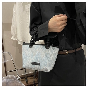 Detail of light blue sequin bucket bag with black leather trim and adjustable strap