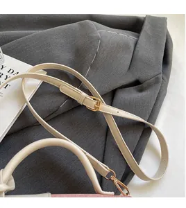 Detail of adjustable cream shoulder strap with gold-tone metal hardware on pink handbag