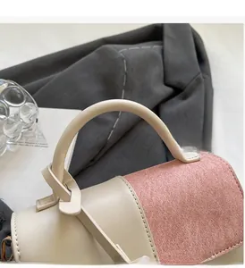 Close-up of contrast stitching and durable handle on bicolor leather crossbody bag