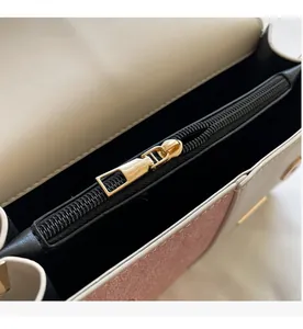 Close-up of smooth gold metal zipper and pink contrast texture on leather crossbody bag