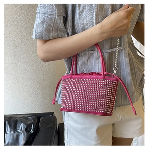 Detail of rose red drawstring bucket bag with sparkling studs and chain strap