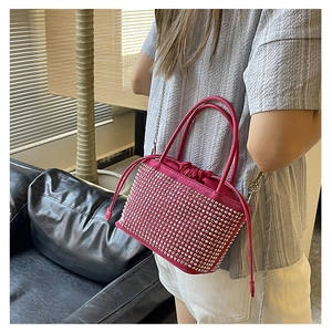 Detail of pink rhinestone bucket bag with silver studs and chain strap shown on a model