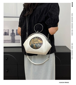 Detail of white shell bag featuring an embossed gold elephant and floral pattern