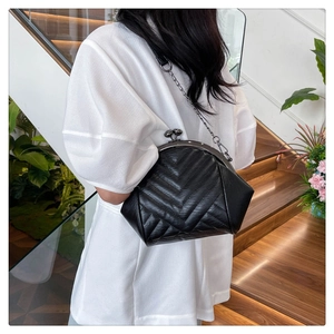 Detail of black shell bag featuring V-shaped quilting and vintage metal kiss-lock closure