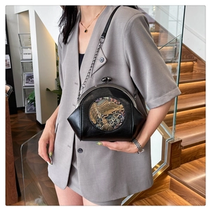 Detail of vintage black shell bag with elephant relief and retro gold clasp closure
