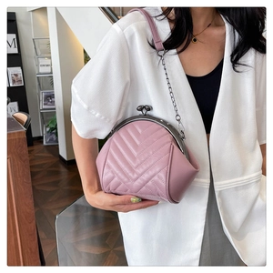 Pink quilted shell crossbody bag with V-shaped stitching and vintage metal clasp