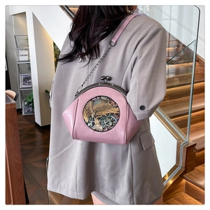 Close-up of pink shell-shaped crossbody bag with vintage bronze elephant relief and chain strap