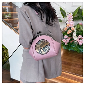 Detailed view of pink lychee leather crossbody bag featuring a vintage elephant relief emblem