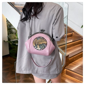 Pink shell bag with elephant relief and bronze chain shown on model's back