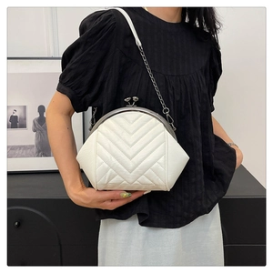 Close-up of white leather shell bag with V-shaped quilting and silver chain strap
