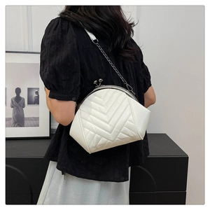 Detail of white quilted shell bag with silver ball clasp and dark metal chain strap