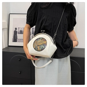 Detail of vintage shell bag with elephant embroidery and golden clasp on a metal chain