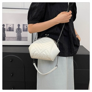 Close-up of white quilted shell bag with V-shaped stitching and silver chain strap
