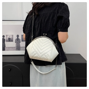Chic white shell-style quilted crossbody bag worn by model with metallic chain and handle