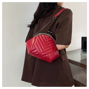 Close-up of red quilted shoulder bag featuring vintage metal clasp and elegant chain strap