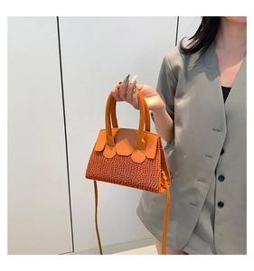 Detail of orange woven texture and smooth leather flap on crossbody handbag